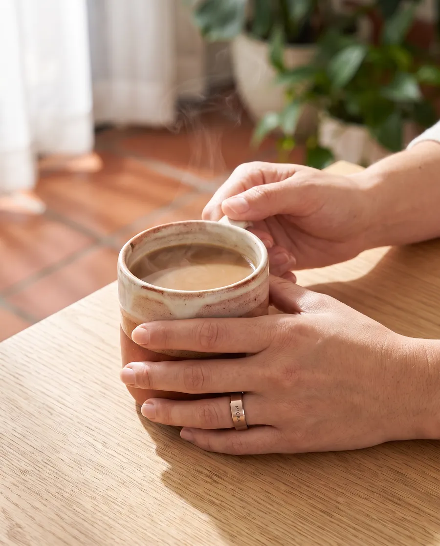 Manos con MICRA Ring sosteniendo una taza de café