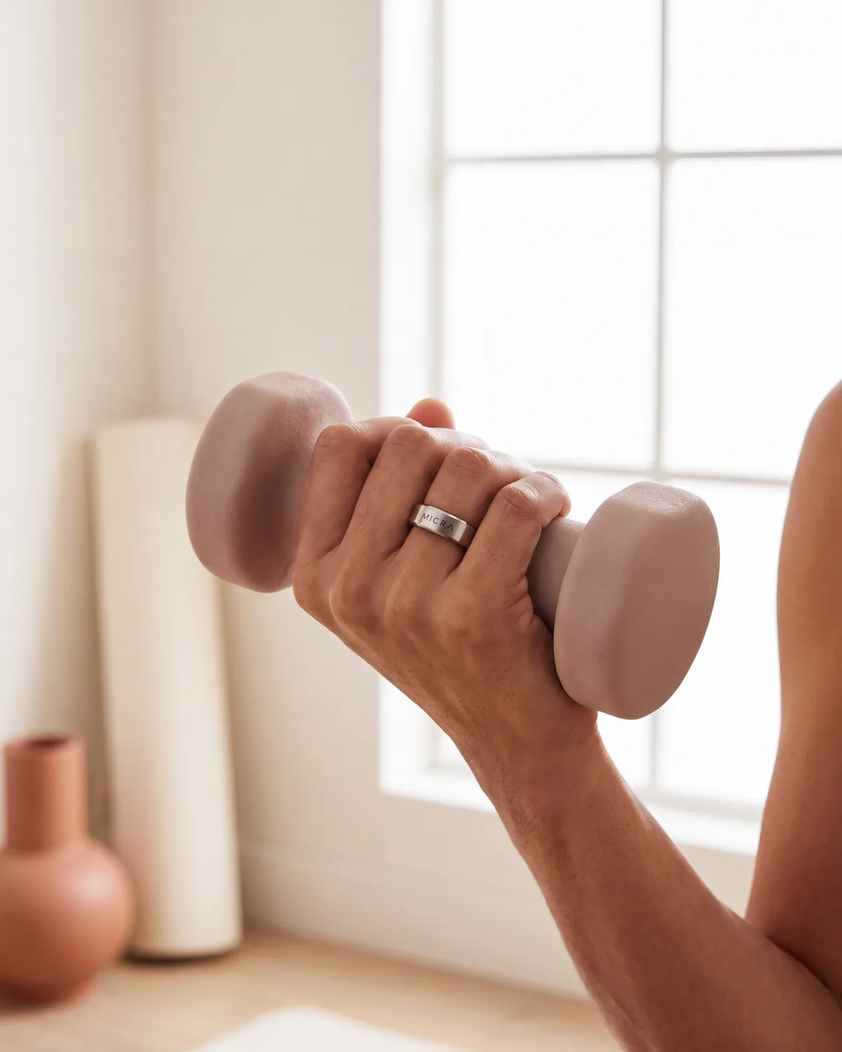 Mano con anillo inteligente ajustando una pesa en un gimnasio en casa