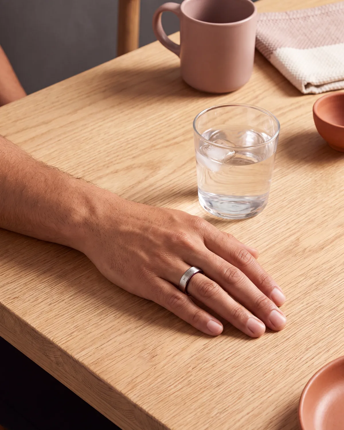 Mano con anillo inteligente apoyada sobre una mesa de madera