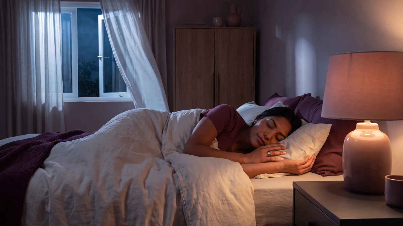 Recámara fresca con ventana abierta y una persona dormida con un anillo inteligente